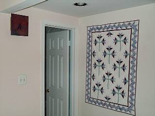 Picture of lily quilt at head of stairway downstairs.